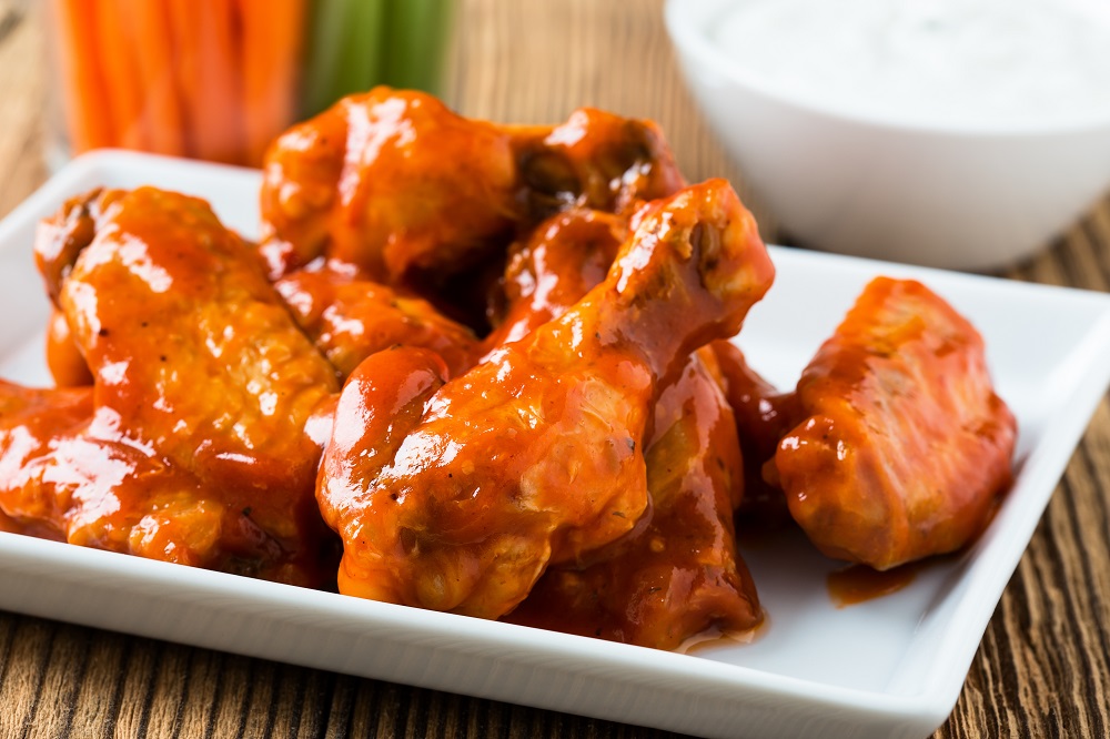 Wings on plate with ranch and carrots behind it.