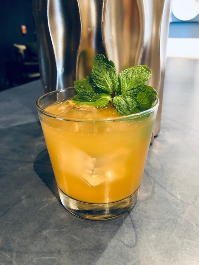 A melon inspired cocktail in a rocks drinking glass.