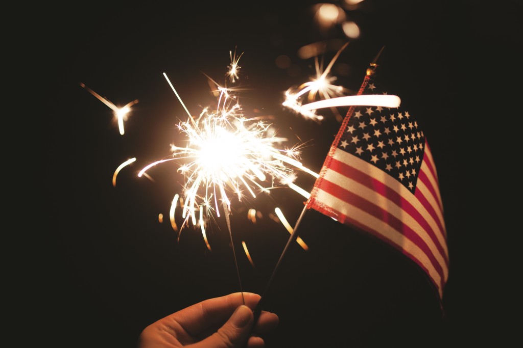 Someone holding an American flag and a sparkler.